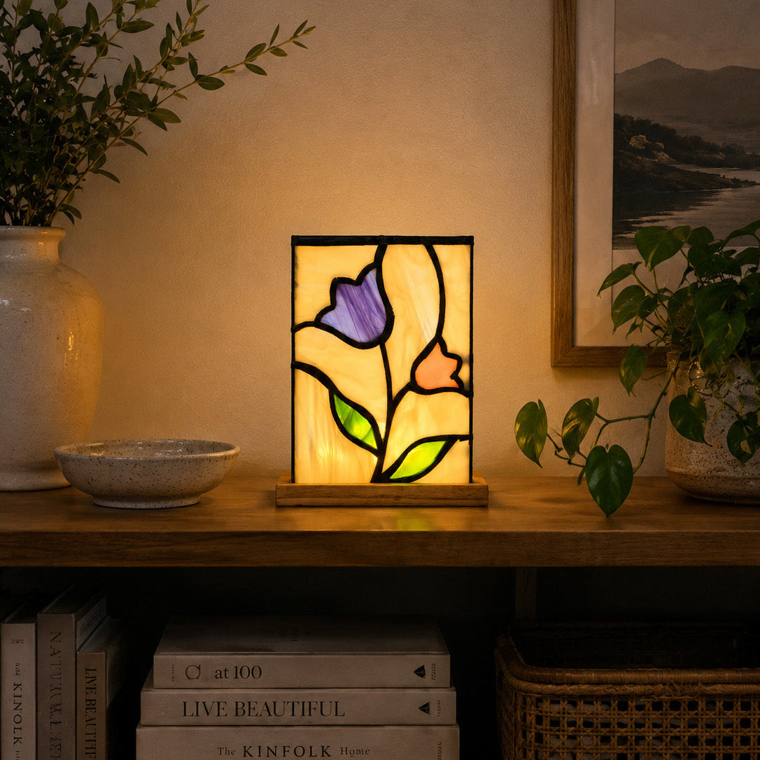 Stained glass lamp on a wooden shelf with books and plants