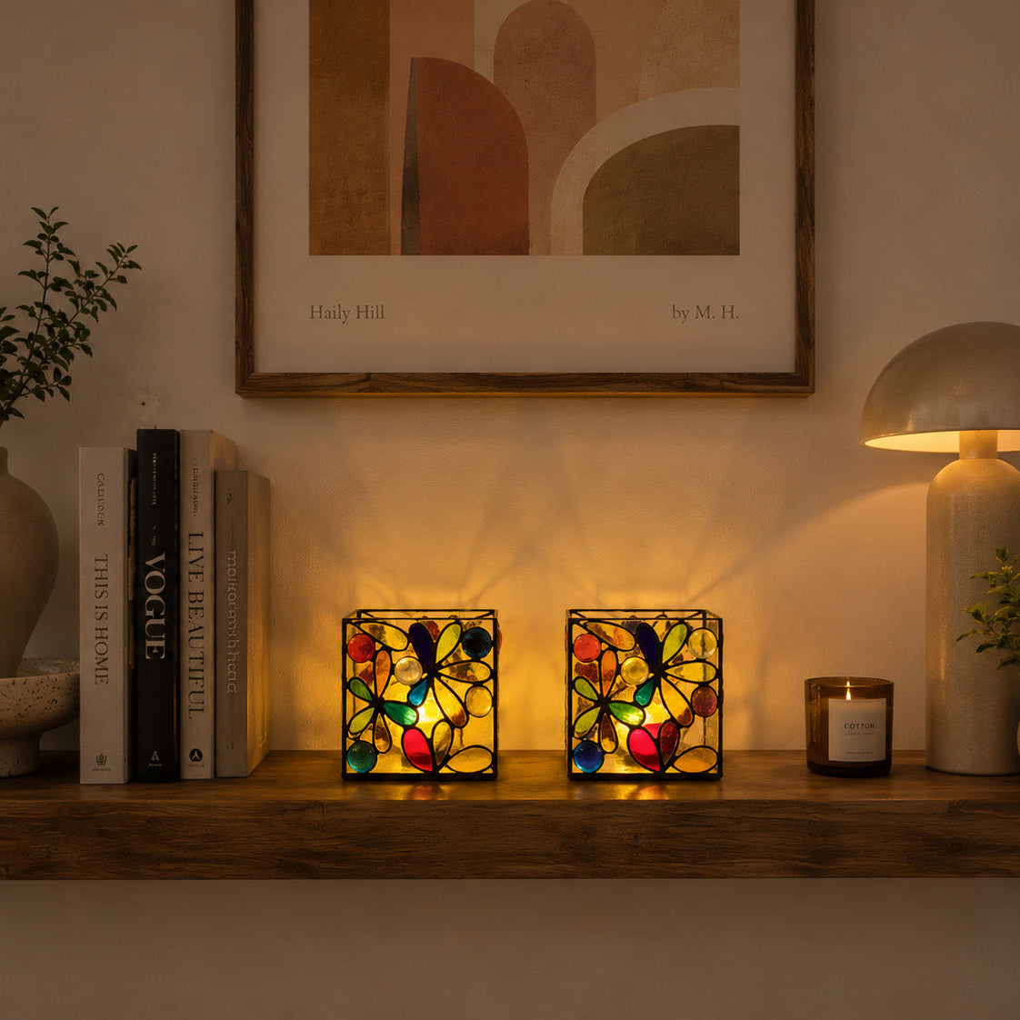 Decorative shelf with stained glass lamps, books, and plants in a warm setting.