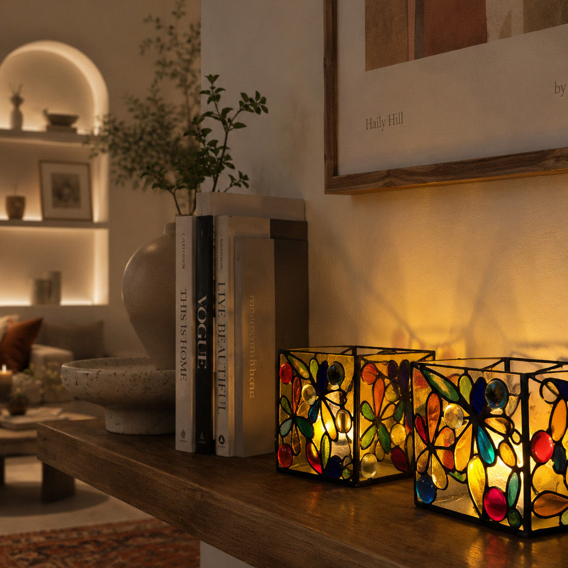 Decorative stained glass lamps on a wooden surface with books and a plant in a living room setting.