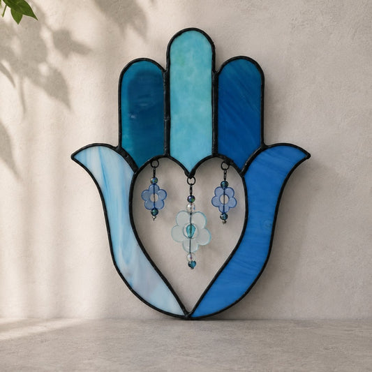 Decorative stained glass hamsa hand with blue and white colors on a neutral background