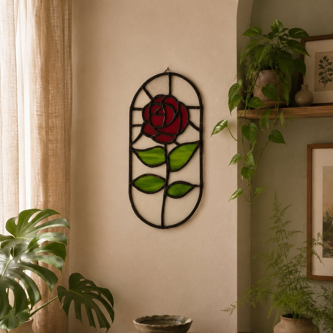 Decorative wall art of a red rose with green leaves on a beige wall, surrounded by plants.