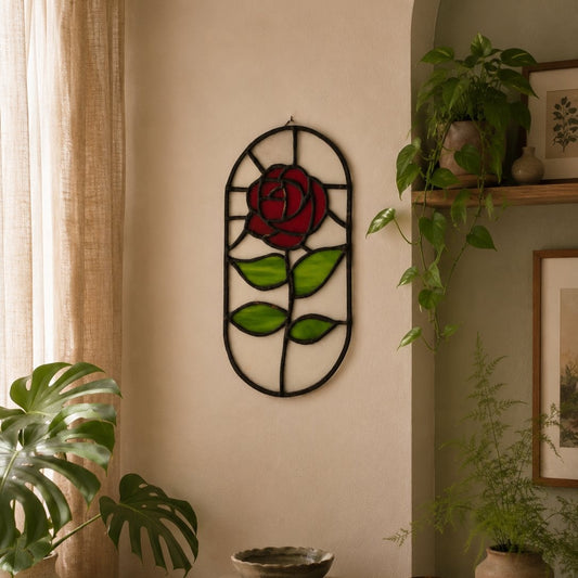 Decorative wall art of a red rose with green leaves on a beige wall, surrounded by plants.