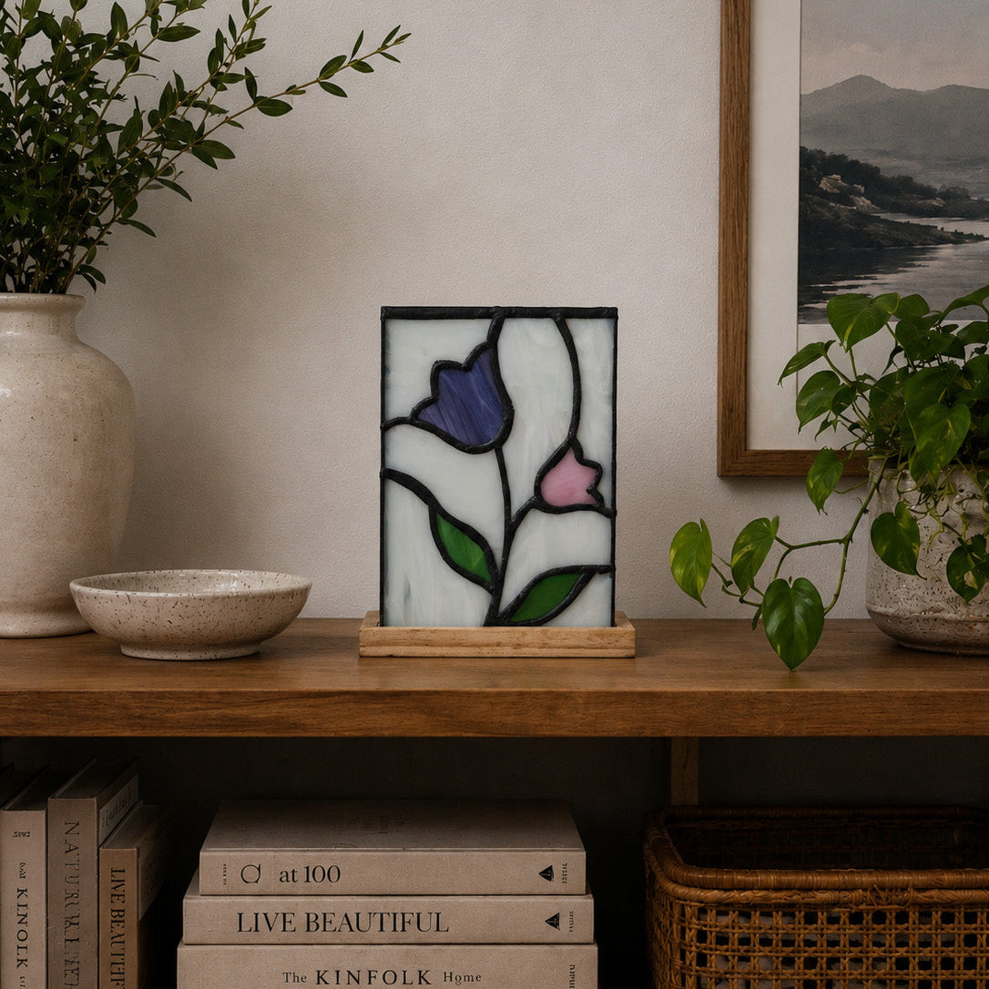 Decorative stained glass lamp on a wooden shelf with books and plants